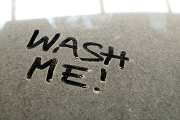 Car dust word on dirty rear window of the car and inscription WASH ME!. Front and side view of mirror. Close up of text with handwriting.