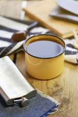 Cup of strong coffee with a flask on a wooden table, close up