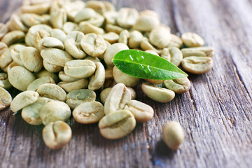Green coffee beans with a leaf on  wooden table