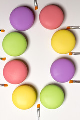 cosmetic macaroons lying in circle, white background, lip brushes