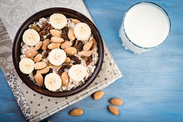 Healthy muesli breakfast with huts and raisins and  milk on blue background.