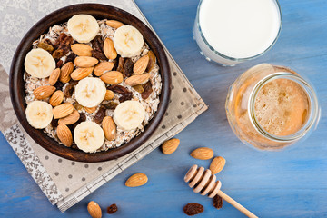 Healthy muesli breakfast with huts and raisins and  milk on blue background.