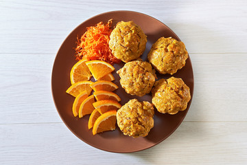 Carotte muffins served on the plate with orange slices, top view