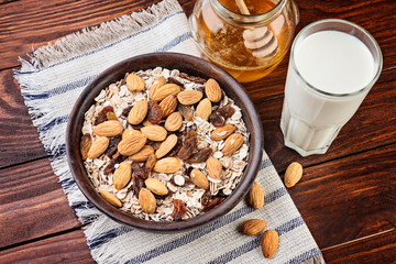 Healthy breakfast. Granola with nuts in a wooden bowl, honey and  milk  on a rustic background