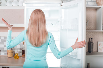 Young blonde at home near fridge