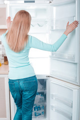 Young blonde at home near fridge