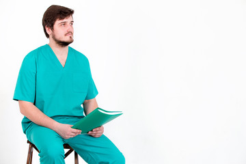 The doctor sits on a chair with folder on a white background.