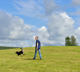 Young man walking with dog in field in northern Finland, Lapland