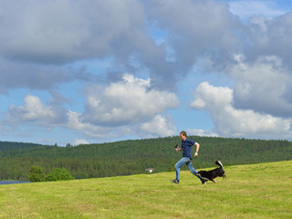Summer landscape. Running young man and dog