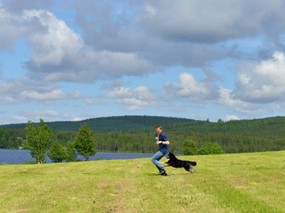 Summer landscape. Running young man and dog