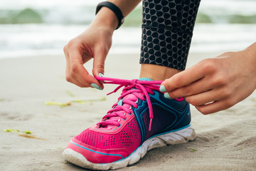 Female hands with manicure tie laces on pink and blue sneakers o
