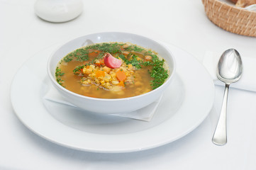 Lentil Soup Served in a White Bowl with Spoon on a restaurant table
