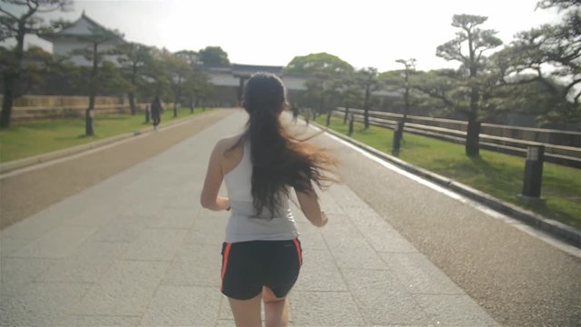 Young Japanese fitness model running in Osaka castle park steadycam follow shot Slow-motion 