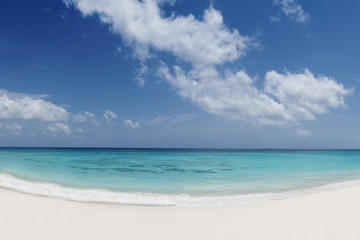 tropical beach with white sand turquoise water and blue cloudy sky