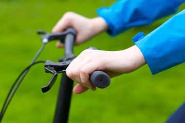 A close up view of a stylish girl riding a bicycle in the green park in summer. Wearing blue stylish clothes.