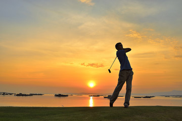 Young man playing golf at sunset