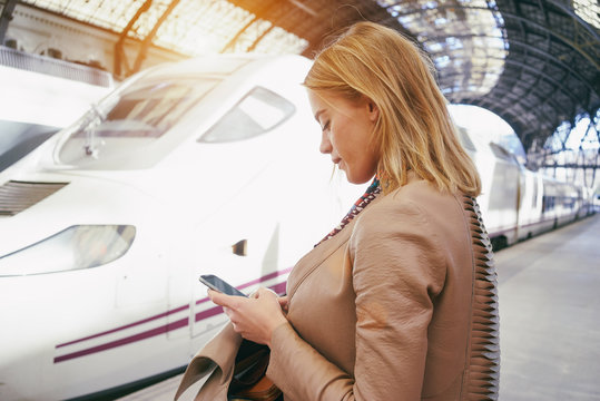 young attractive businesswoman booking of train tickets online.beautiful young blonde woman writes a text message on her smart-phone. flare light