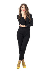 Fototapeta premium Daydreaming brunette beauty in black overalls looking up. Full body length portrait isolated over white studio background.