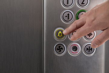 Hand  pressing the alarm button in the elevator