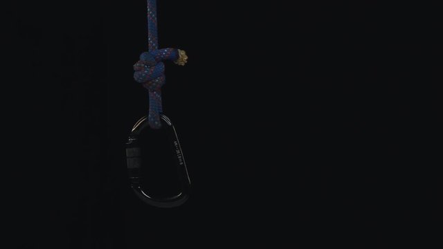 Rope with carabine on black background. Slow motion