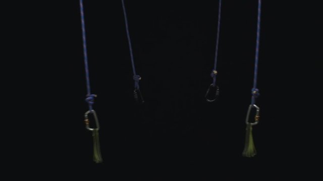 Rope with carabine on black background. Slow motion