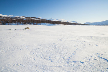 Fototapeta na wymiar Winterzelten auf einem zugefrorenen See in Schweden