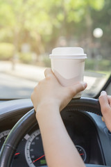 Women holding white coffee cup and drinking while driving, morni
