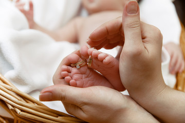 Baby's feet with wedding rings on fingers in mother's hands