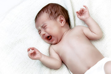 Cute newborn baby crying in white bad