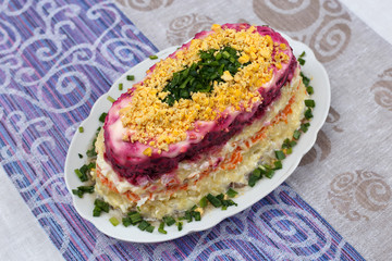 Colorful salad with herring and vegetables on the plate