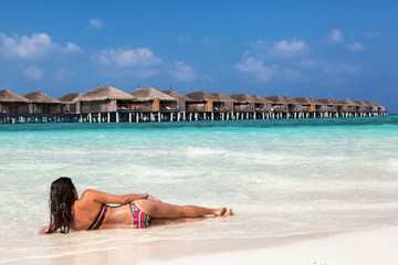 Frau liegt am Strand der Malediven und schaut auf den Horizont