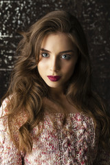 Young brunette woman on dark studio wall background