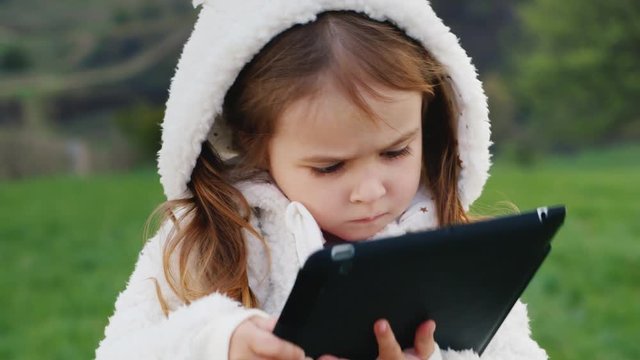 Very serious girl 3 years old with a tablet