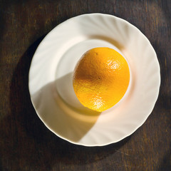 Ripe orange in white plate on wooden background