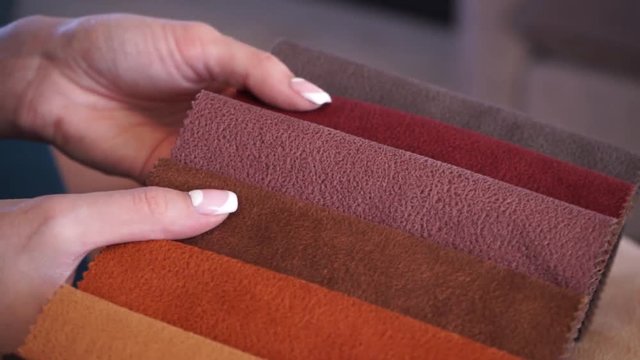 textiles. Girl leafing through tissue samples for sofa upholstery
