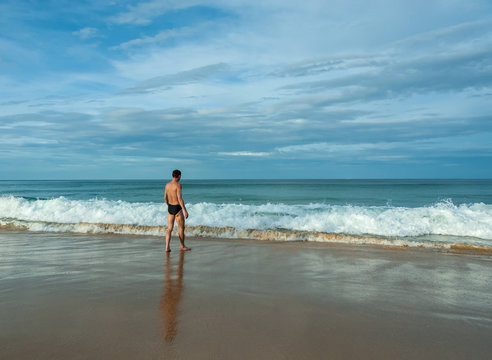 a man stands on the beach and watching the waves