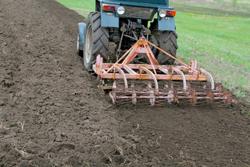 Tractor with cultivator harrow the ground fastened. Summer seaso