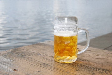 Kühles, frische Bier /  Bierkrug mit frischem Bier draußen am See  