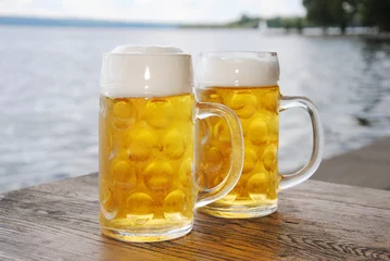 Selbstklebende Fototapeten Bier Kühles, frische Bier / Zwei Bierkrüge mit frischem Bier draußen am See    © Sabrina  Cercelovic