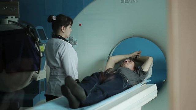 Mid adult nurse preparing patient for CT scan test in hospital 