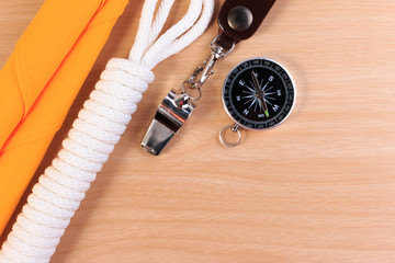 Fototapeta premium Orderliness white scout rope, scarf, whistle and compass on wooden table.