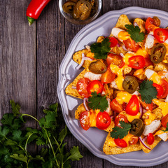 Nachos with melted cheese sauce, jalapeno, chicken and vegetable