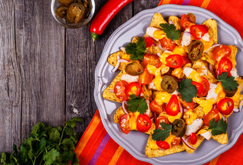 Nachos with melted cheese sauce, jalapeno, chicken and vegetable