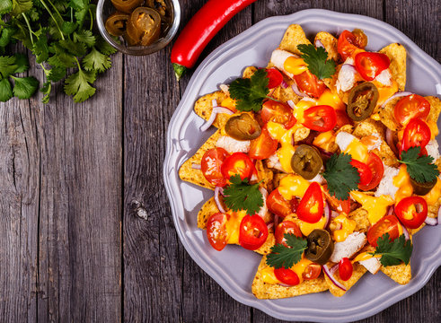 Nachos with melted cheese sauce, jalapeno, chicken and vegetable