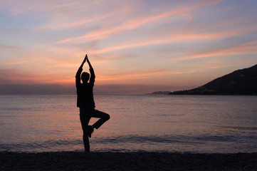 Fototapeta na wymiar Yoga silhouette on the beach at sunset