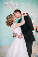 Naklejka premium Happy couple. Wedding photo shoot in the white studio with wedding decor kisses, hugs