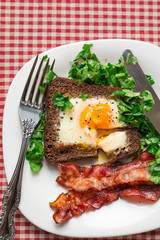 Fried egg in rye bread with bacon and parsley