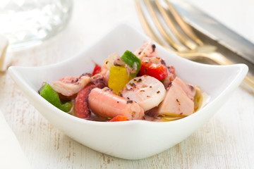 salad with octopus in bowl on white wooden background