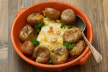 cod fish with potato in ceramic dish on brown wooden background