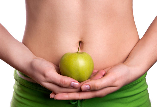 Sporty belly with apple in woman's hands